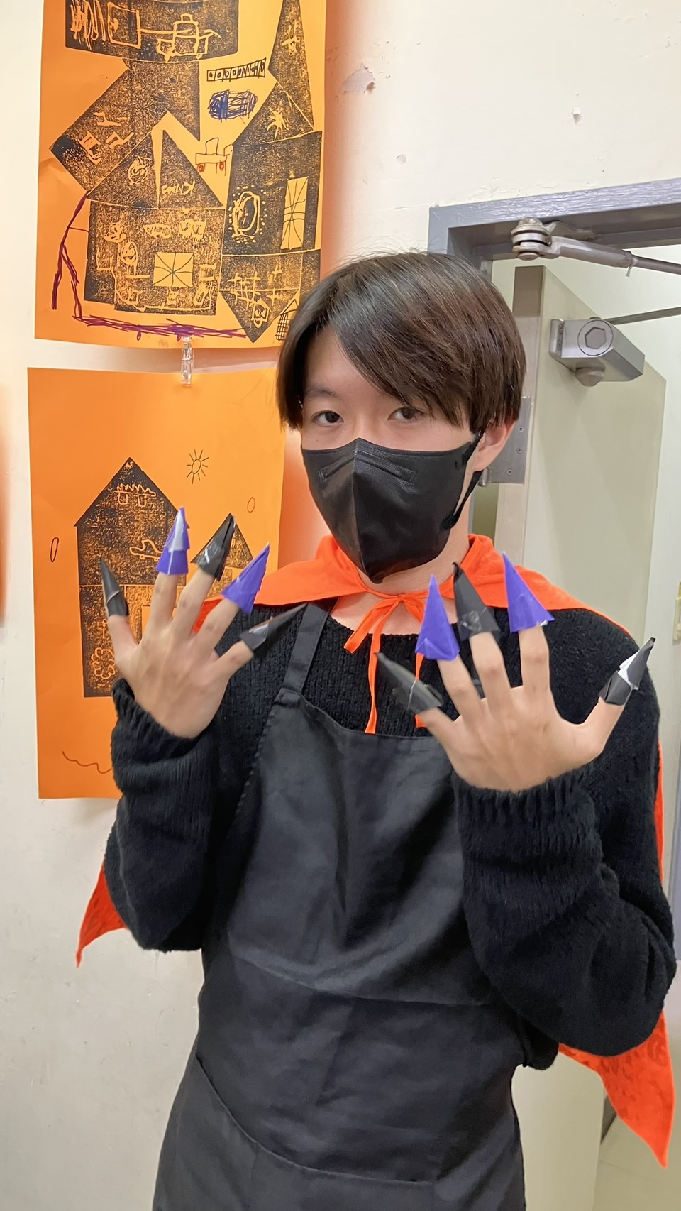 オレンジのマントと手作りの紙の爪で、ハロウィンの仮装を楽しむワークショップの様子